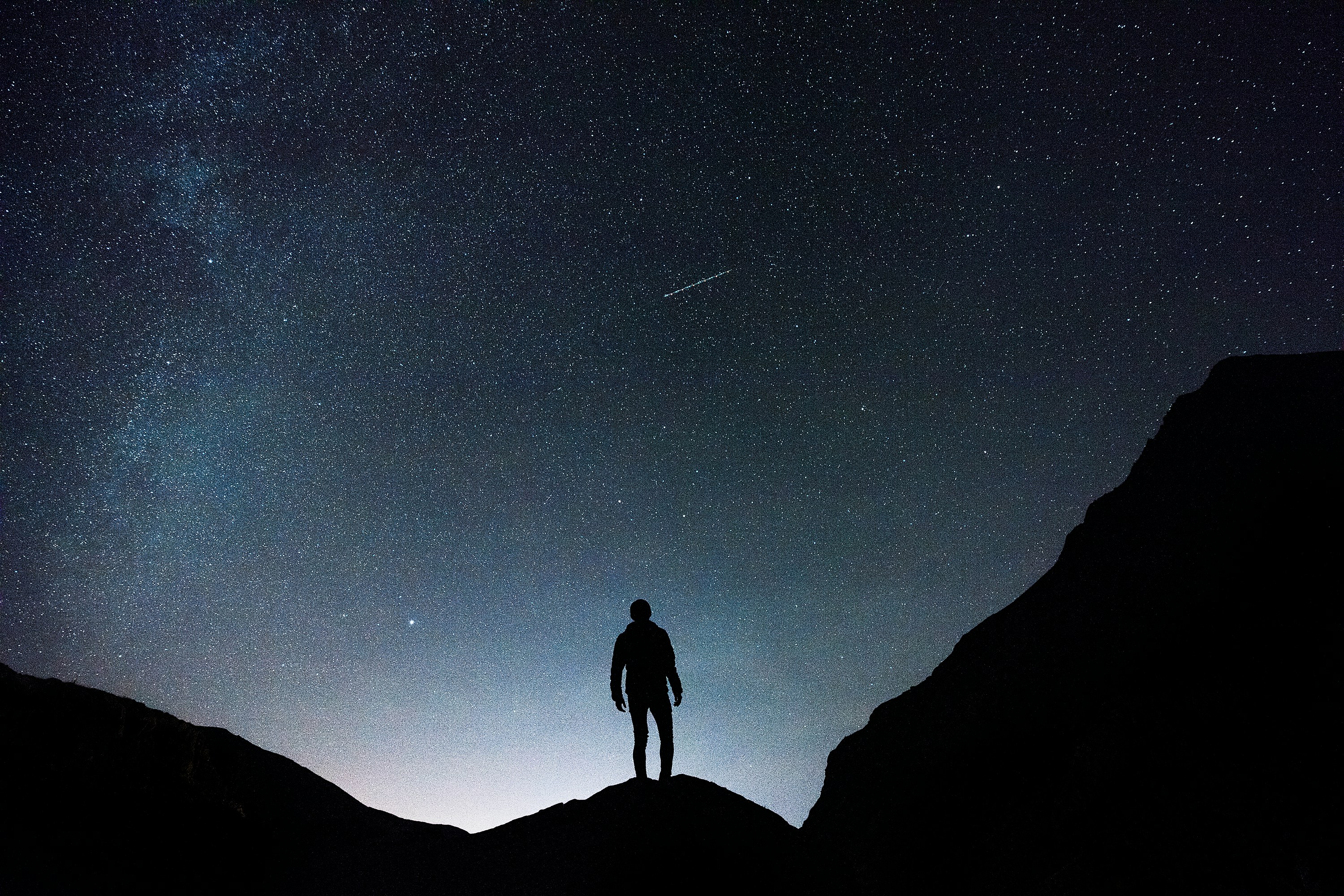 Silouhette d'un homme, de dos, face à un ciel étoilé
